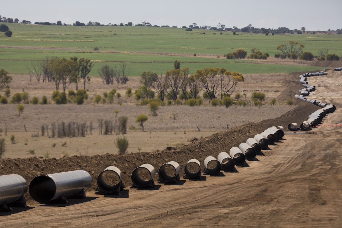 Coated steel pipes laid out along a pipeline right-of-way curving through farmland