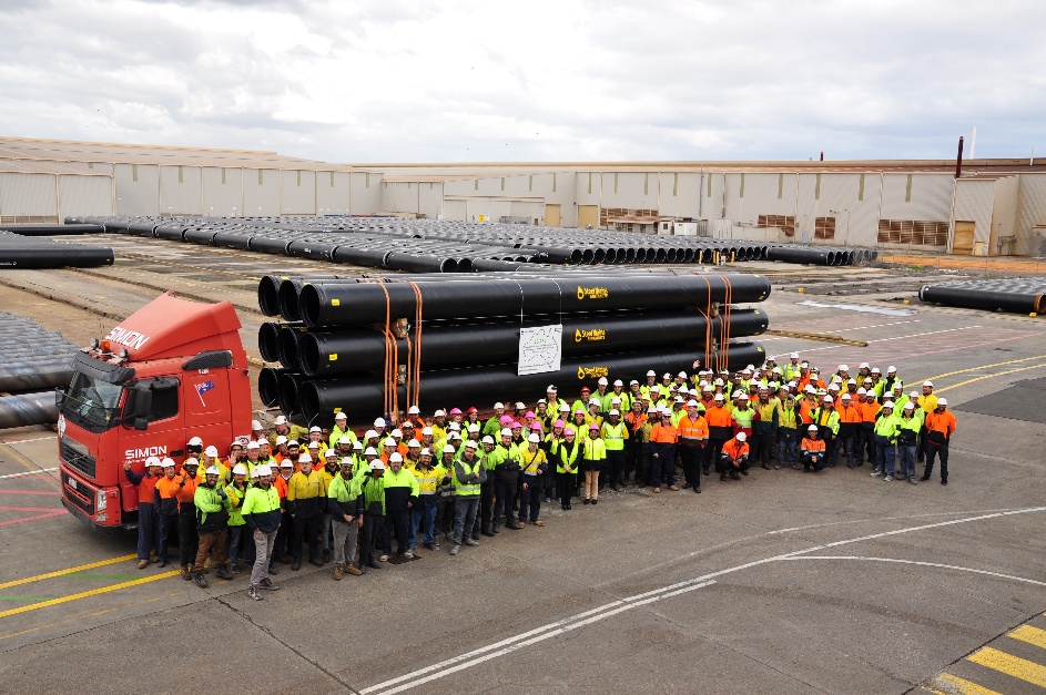 The Steel Mains workforce in front of stacked Sintakote pipes at the plant